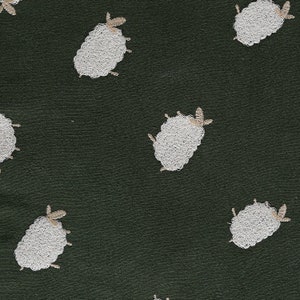 Puede incluir: Una tela verde oscuro con un patr&oacute;n repetido de ovejas bordadas blancas. Las ovejas son estilizadas y tienen un dise&ntilde;o simple.