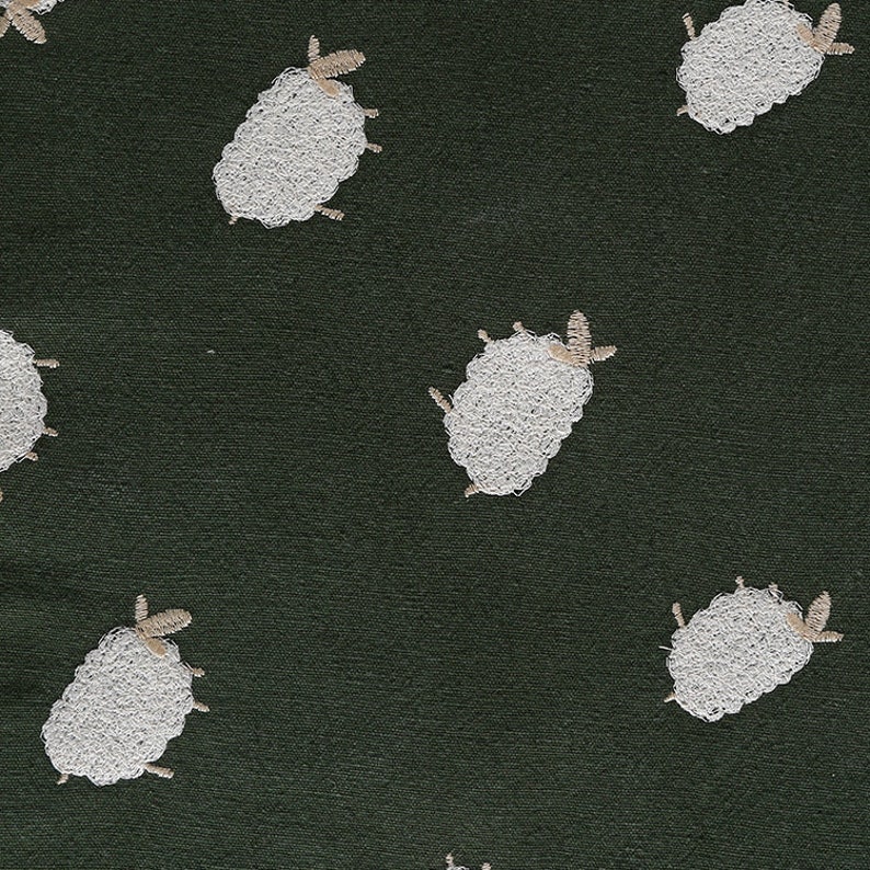 Puede incluir: Una tela verde oscuro con un patr&oacute;n repetido de ovejas bordadas blancas. Las ovejas son estilizadas y tienen un dise&ntilde;o simple.