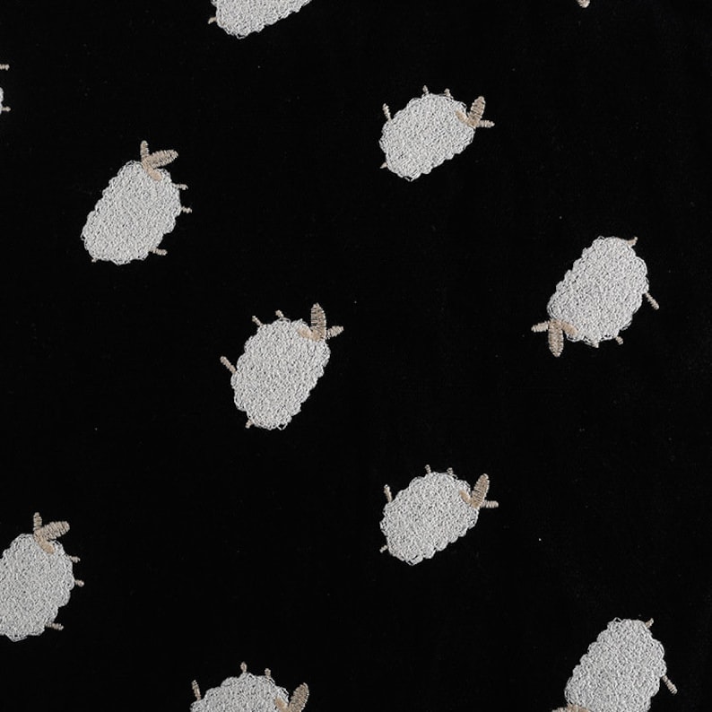 Puede incluir: Tela negra con un patr&oacute;n repetido de ovejas bordadas en blanco.