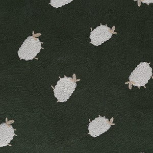 Puede incluir: Una tela verde oscura con un patr&oacute;n repetido de ovejas bordadas en blanco.
