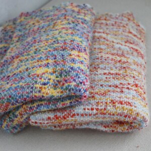 May include: Two folded pieces of textured knit fabric. The left piece features a dense, multicolored speckled pattern of blue, yellow, red, and purple. The right piece displays a lighter, horizontal-striped pattern of orange, red, and white.