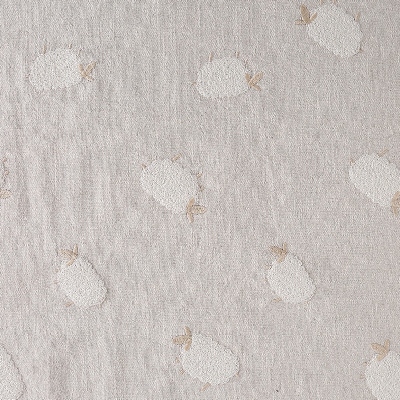 Puede incluir: Una tela beige con un patr&oacute;n repetido de ovejas bordadas blancas. Las ovejas son estilizadas y tienen un dise&ntilde;o simple.