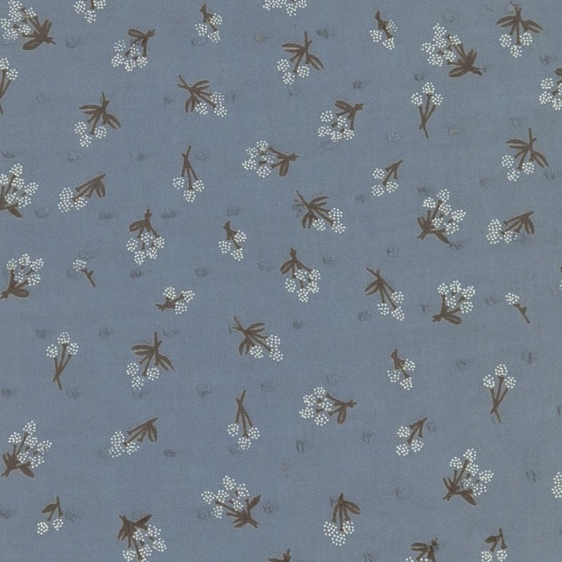Op de afbeelding: Een blauwe stof met een wit en bruin bloemenpatroon. De bloemen zijn klein en delicaat, en de stof heeft een subtiele textuur.