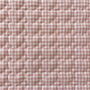 May include: A quilted fabric featuring a repeating pattern of raised, heart-shaped sections. The textile is covered in a pink and white gingham check print, with visible stitching outlining each individual heart shape across the surface.
