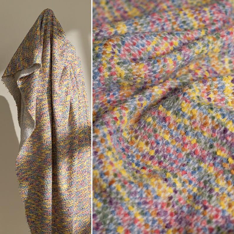 May include: A textured fabric featuring a multi-colored speckled pattern with vibrant hues of yellow, pink, blue, and purple. The material has a soft, fuzzy surface with a woven appearance, showing a dense arrangement of small, colorful dots.