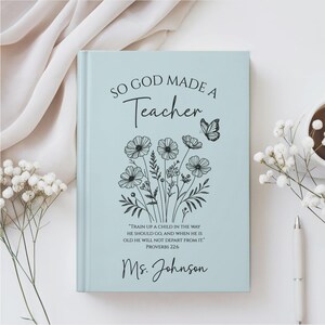 May include: A light blue journal with the text "SO GOD MADE A Teacher" and a floral design. The journal also includes the quote "TRAIN UP A CHILD IN THE WAY HE SHOULD GO, AND WHEN HE IS OLD HE WILL NOT DEPART FROM IT." and the name "Ms. Johnson".