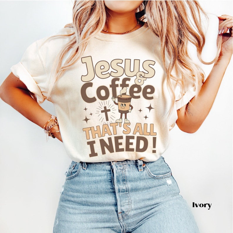 May include: A white t-shirt with the text "Jesus & Coffee That's All I Need!" in brown lettering. A cartoon coffee cup with a face and a cross are also on the shirt.