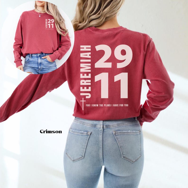 Op de afbeelding: Crimson langarm T-shirt met de tekst "JEREMIAH 29:11 FOR I KNOW THE PLANS I HAVE FOR YOU" gedrukt op de achterkant in wit. Het shirt wordt gedragen door iemand die een blauwe jeans draagt.