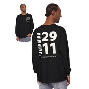 Op de afbeelding: Zwart langarm T-shirt met witte tekst op de rug die "Jeremia 29:11" en "Want ik weet welke plannen ik voor jullie heb" luidt.