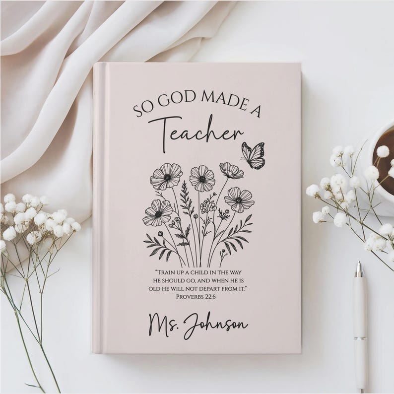 May include: A light pink journal with the text "SO GOD MADE A Teacher" and a floral illustration. The journal also includes the quote "TRAIN UP A CHILD IN THE WAY HE SHOULD GO, AND WHEN HE IS OLD HE WILL NOT DEPART FROM IT." and "Ms. Johnson".