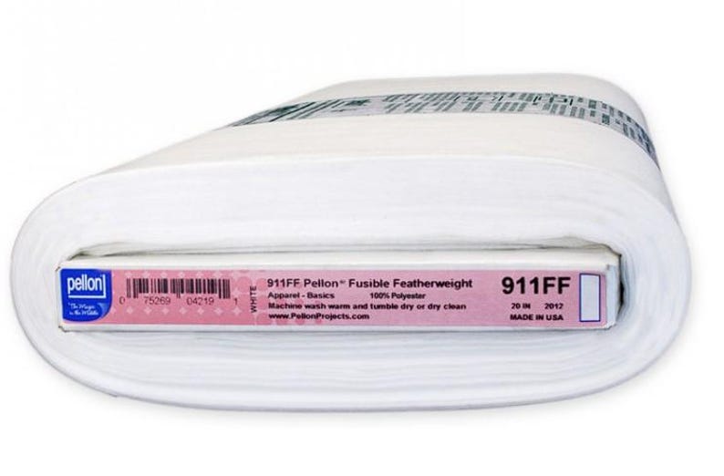 Peut inclure: Rouleau de tissu blanc Pellon 911FF Fusible Featherweight. L'&eacute;tiquette indique "Apparel-Basics" et "100% Polyester". Le rouleau mesure 50.8 cm de large et est fabriqu&eacute; aux &Eacute;tats-Unis.
