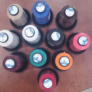 May include: Ten spools of thread in various colors, including red, orange, yellow, green, blue, brown, white, and black. Each spool is labeled "Glide 60".