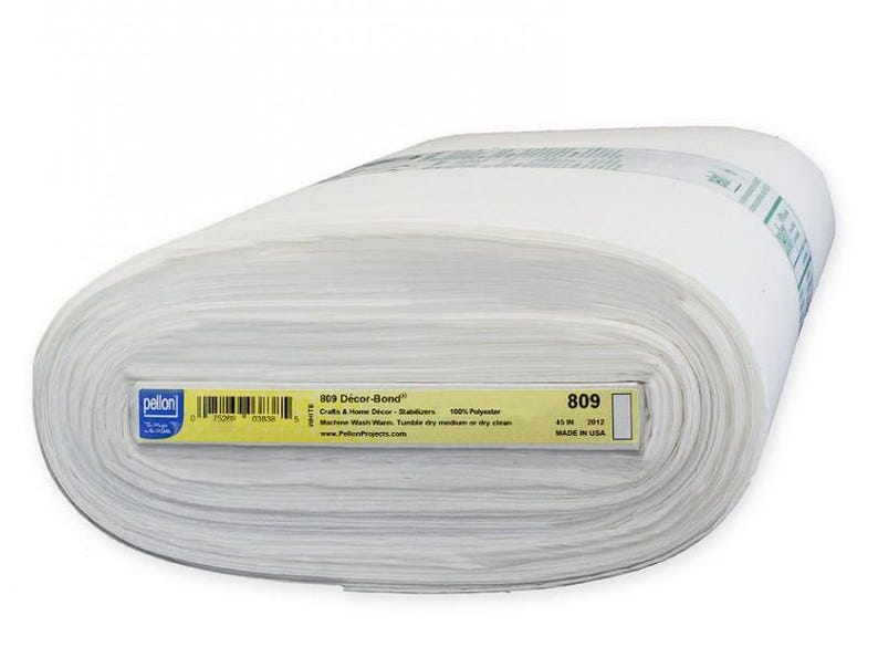 Peut inclure: Un rouleau de tissu blanc avec l'&eacute;tiquette "809 D&eacute;cor-Bond". L'&eacute;tiquette jaune indique que le tissu mesure 114 cm de large et est compos&eacute; &agrave; 100 % de polyester. Le tissu est destin&eacute; aux travaux manuels et &agrave; la d&eacute;coration int&eacute;rieure.