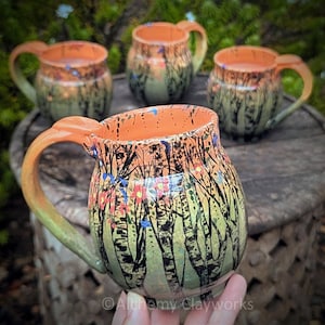 Cuatro tazas hechas a mano con temática de bosque al atardecer