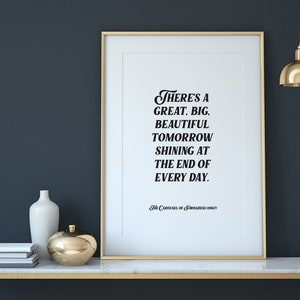 May include: A framed print with a gold frame and a white background. The print features a black and white quote that reads "There's a great, big, beautiful tomorrow shining at the end of every day." The quote is attributed to "The Carousel of Progress" at the bottom of the print.