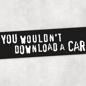 Peut inclure: Panneau rectangulaire noir avec le texte blanc "YOU WOULDN'T DOWNLOAD A CAR". Le texte est en gras, en police sans empattement. Le panneau est pos&eacute; sur un fond gris clair.