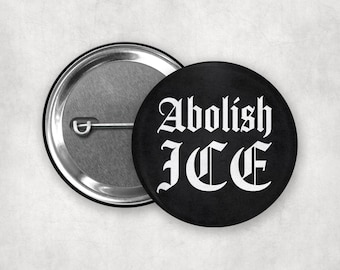 Puede incluir: Botón negro con el texto "Abolish ICE" en letras góticas blancas. El botón es redondo y tiene una parte trasera de metal plateado con un alfiler. Declaración política.