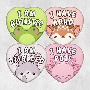 May include: Four heart-shaped badges with animal illustrations and text. The badges are green, pink, and white. The text reads "I AM AUTISTIC", "I HAVE ADHD", "I AM DISABLED", and "I HAVE POTS".