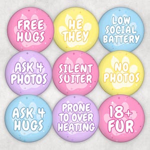 May include: Nine colorful round buttons with text, including "Free Hugs," "He/They," and "Low Social Battery." Each button features a paw print design and various phrases in white text on pastel backgrounds.