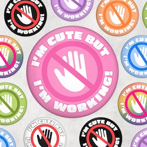 Op de afbeelding: Een verzameling kleurrijke ronde buttons met de tekst "I'm Cute But I'm Working!" in het wit. Elke button heeft een hand symbool met een rood verbodsteken. De buttons zijn in verschillende kleuren, waaronder roze, blauw, groen en oranje.
