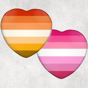May include: Two heart-shaped designs. One features a gradient of orange, yellow, and white stripes. The other has pink and white stripes. Both have a glossy finish and are set against a textured, off-white background.