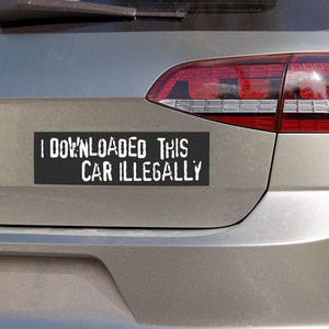 Peut inclure: Un autocollant de pare-chocs rectangulaire noir avec le texte blanc "I DOWNLOADED THIS CAR ILLEGALLY" est appos&eacute; &agrave; l'arri&egrave;re d'une voiture argent&eacute;e. Le feu arri&egrave;re rouge de la voiture est visible.