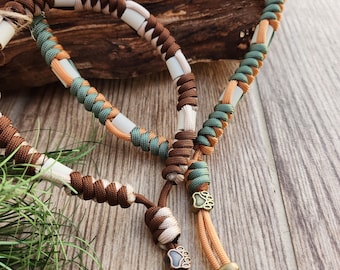 May include: Two braided paracord bracelets with brown, green, and white woven strands. The bracelets have a paw print charm on the end of each.