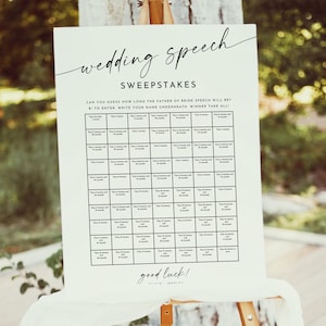 Peut inclure: Panneau blanc pour un jeu de devinettes de discours de mariage sur un chevalet en bois. Le panneau comporte une grille pour que les invités écrivent leurs noms et devinent la durée du discours. Le texte dit "wedding speech sweepstakes" et "bonne chance!"
