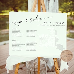 May include: A white sign with black text on an easel. The sign says "Sip & Solve Emily + Wesley Grab a drink & see if you can solve our crossword". The sign has a crossword puzzle with clues listed on the side. The sign also says "Includes Step-by-Step Instructions Tutorial".