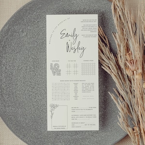 May include: A printable wedding reception game card with a black and white design. The card features a word search, connect four, noughts and crosses, and a love maze. The card also includes the text "Welcome to the Wedding of Emily + Wesley".