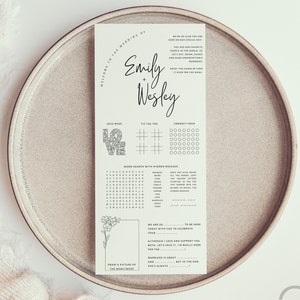 May include: A printable wedding reception activity sheet featuring games such as a love maze, noughts and crosses, connect four, and a word search with a hidden message. The sheet also includes a space to draw a picture of the newlyweds and a quote about marriage. The sheet is printed on white paper with black ink.