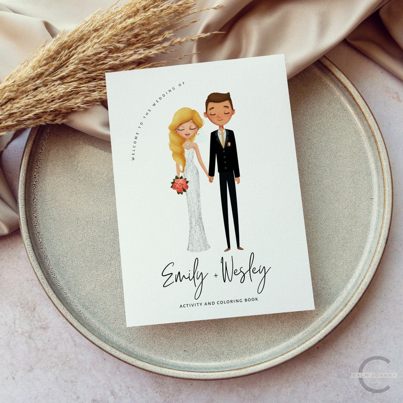 May include: A white card with a cartoon illustration of a bride and groom. The bride is wearing a white dress and the groom is wearing a black suit. The text on the card reads "Welcome to the wedding of Emily + Wesley Activity and Coloring Book".