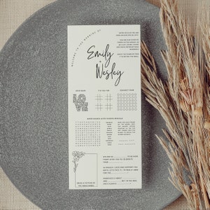 K&ouml;nnte beinhalten: Ein druckbares Hochzeitsempfangs-Aktivit&auml;tsblatt mit Spielen wie einem Liebeslabyrinth, Tic-Tac-Toe, Vier gewinnt und einer Wortsuche. Das Blatt ist beige mit schwarzem Text und Grafiken. Der Text oben lautet "Willkommen zur Hochzeit von Emily + Wesley".