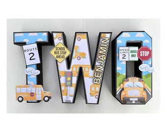 May include: A three-dimensional wooden letter set spelling out "TWO" with a school bus theme. The letters are decorated with images of school buses, traffic signs, and the name "Benjamin".