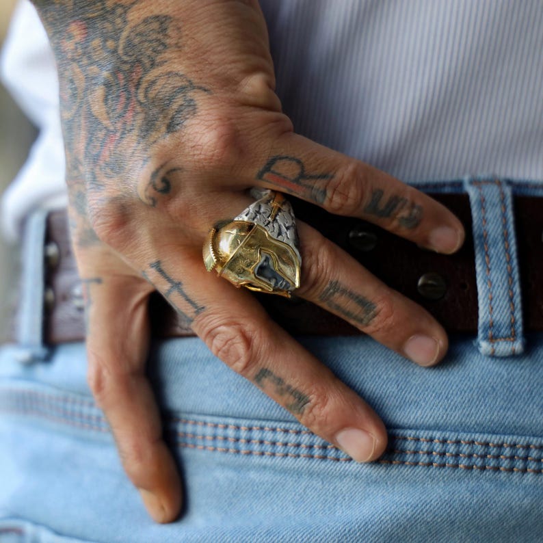 Styled on the finger, this men’s 14K gold plated Spartan ring exudes bold style and ancient Greek elegance. The substantial design, weighing 27 grams, commands attention and celebrates the warrior spirit within, making it a striking addition to any man’s jewelry collection and a symbol of strength and resilience.