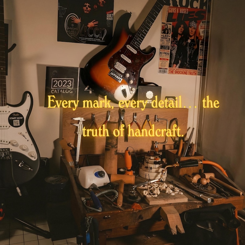 K&ouml;nnte beinhalten: Werkstatt mit Werkzeugen und Gitarren. Der Text lautet: &bdquo;Jede Markierung, jedes Detail... die Wahrheit des Handwerks.&ldquo; Eine Fender-Gitarre befindet sich links, und eine Sunburst-E-Gitarre h&auml;ngt &uuml;ber der Werkbank.