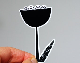 Könnte beinhalten: Schwarz-weißer Aufkleber einer stilisierten Blume mit einem einzigen Blatt. Die Blume hat einen abgerundeten, becherförmigen Kopf und einen langen, dünnen Stiel.