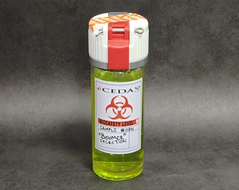 May include: A clear cylindrical vial filled with a bright neon yellow liquid. The white cap features a red locking mechanism and a metal pin. A white label displays the CEDA logo, a biohazard symbol, and the text: BIOSAFETY LEVEL, SAMPLE #0841, BOOMER EXCRETION.