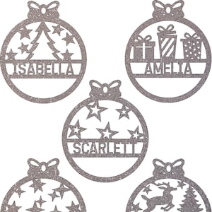 May include: Five silver glitter Christmas baubles with different designs. Each bauble has a space for a name. The names are "Isabella", "Amelia", "Scarlett", "William", and "Theodore".