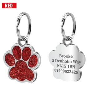 May include: Silver paw print dog tag with a red glitter paw print design. The tag has the text "Brooke, 5 Denholm Way, KA15 1BN, 07490622428" engraved on it.