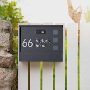 May include: A dark grey mailbox fixed to a white fence. The mailbox displays the address "66 Victoria Road" in white. It has a combination lock and three grey squares on the front.