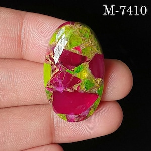 May include: An oval-shaped gemstone featuring a mosaic pattern of vibrant magenta and lime green segments separated by thin metallic copper-colored veins. The surface has a faceted finish and the text M-7410 is visible in the upper right corner.