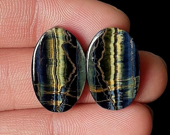 May include: Two oval-shaped gemstones with a striking pattern of blue, gold, and brown streaks. The gemstones are polished and have a glossy finish. The text "M-6317" is visible in the upper right corner. These gemstones are ideal for jewelry making.