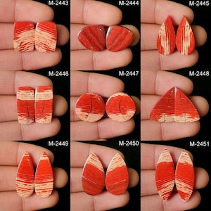May include: Twelve pairs of red and white striped cabochons, each pair is labelled with a unique code, M-2443 through M-2451. The cabochons are various shapes, including teardrop, oval, and rectangular.