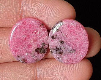 May include: Two oval-shaped, polished gemstones with a vibrant pink hue and dark inclusions. The stones are set against a dark background, with the text "M-6516" in the upper right corner. These gemstones are likely for jewelry making.