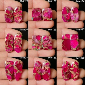 May include: A collection of nine pairs of polished gemstones in various shapes. The stones feature a vibrant pink hue with gold and white veining. Each pair is displayed against a neutral background, showcasing the unique patterns and colors.