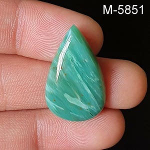 May include: A teardrop-shaped gemstone with a polished surface. The stone features a blend of green and white hues with natural veining and a glossy finish. The text "M-5851" is visible in the upper right corner.