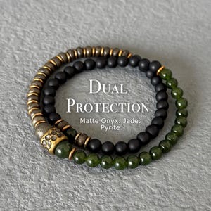 May include: Two beaded bracelets. One bracelet features matte black onyx beads, and the other features green jade beads. The bracelets are layered with a gold-coloured pyrite accent. The text "Dual Protection" is displayed.
