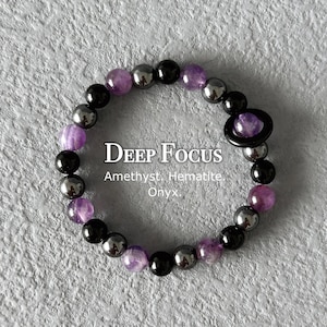May include: A beaded bracelet featuring amethyst, hematite, and onyx stones. The bracelet has a mix of purple, black, and silver beads. The text "DEEP FOCUS" and the stone names are visible.