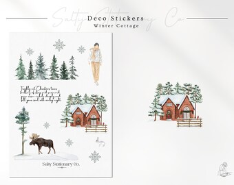 May include: Watercolor sticker sheet featuring winter cottage and forest scenes. Includes illustrations of a house, trees, snowflakes, a moose, and a person in winter attire. The text on the sheet reads "Winter Cottage" and "Freshly cut Christmas trees..."